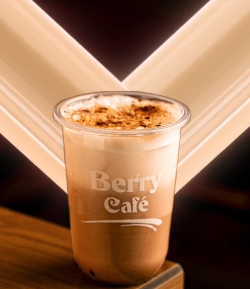 A frothy iced coffee dusted with cinnamon in a Berry Café cup