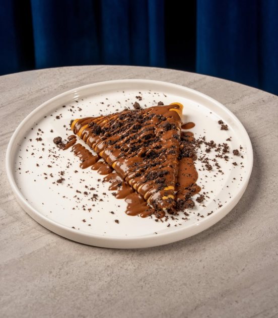 A chocolate crepe topped with cookie crumbs