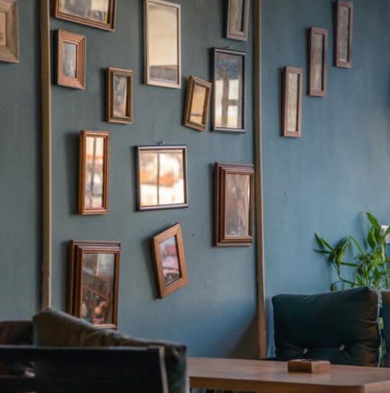 A teal wall covered in vintage picture frames