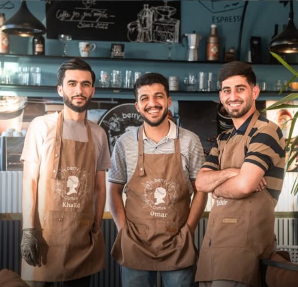 Three smiling baristas in Berry Coffee aprons in front of the counter